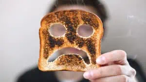 man holding burnt toast sad face