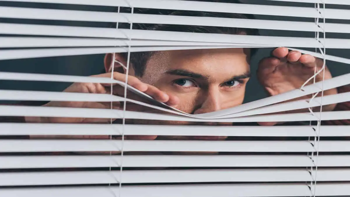 man spying through blinds